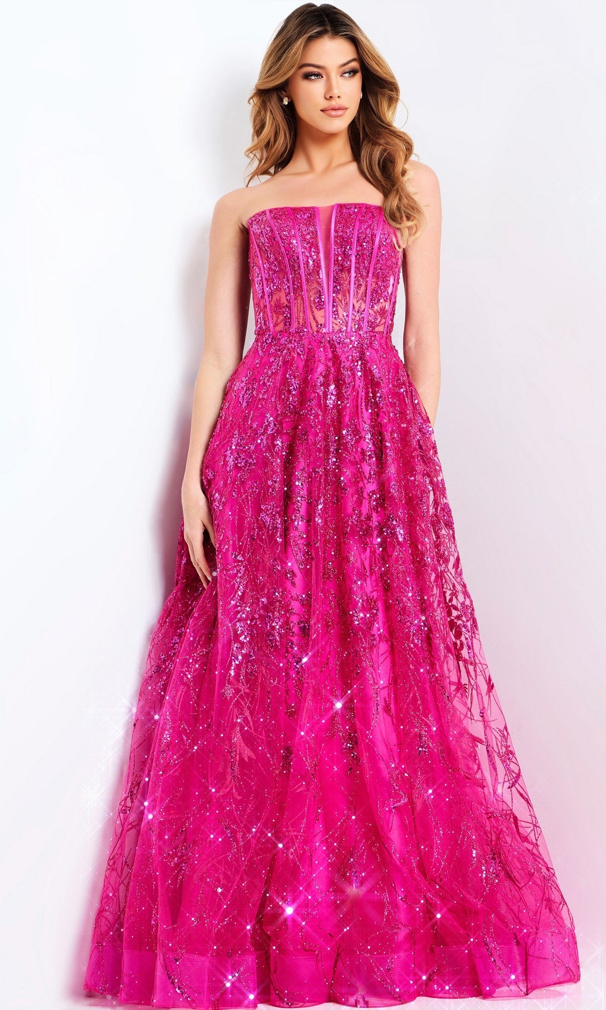 A woman stands against a plain white background wearing the Jovani 45913 long prom dress—a strapless gown with a fitted corset bodice, flared skirt, and hot pink sequin embellishments.